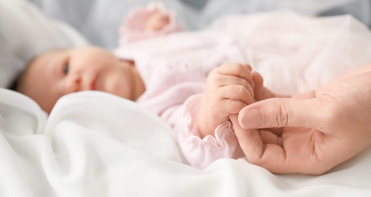 Cute little baby holding mother's hand, closeup